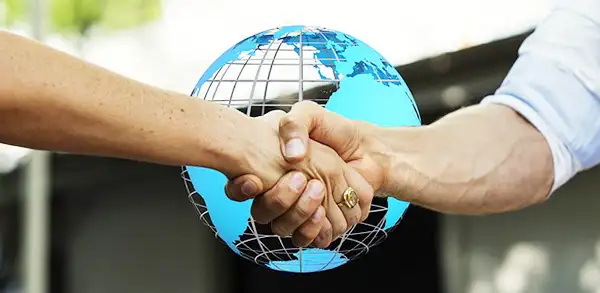 Two hands clasped together with a blue globe behind them