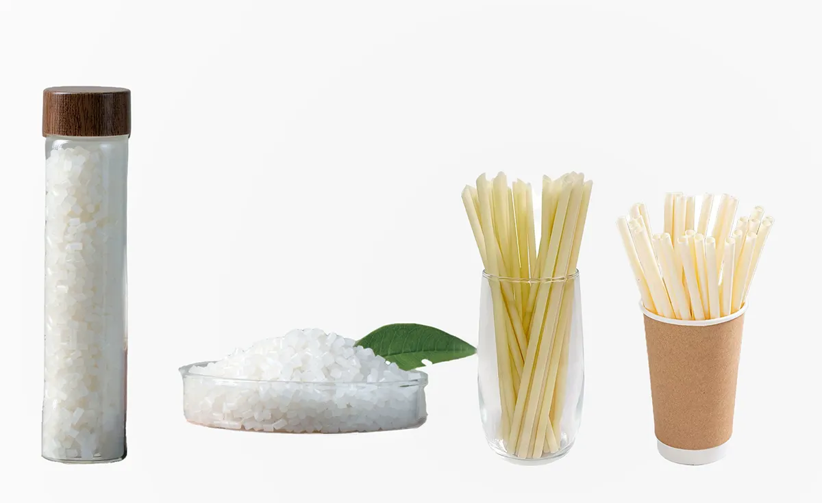 High-performance PHA resin pellets in a glass jar and petri dish next to finished bio-based drinking straws.