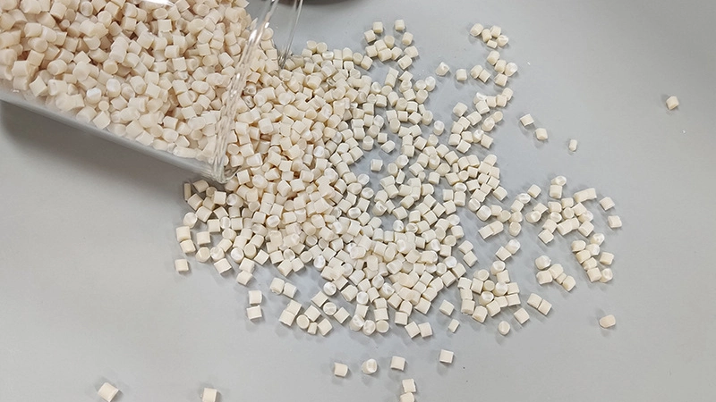 PLA+PBAT modified biodegradable plastic pellets spilled from a glass container on a clean surface