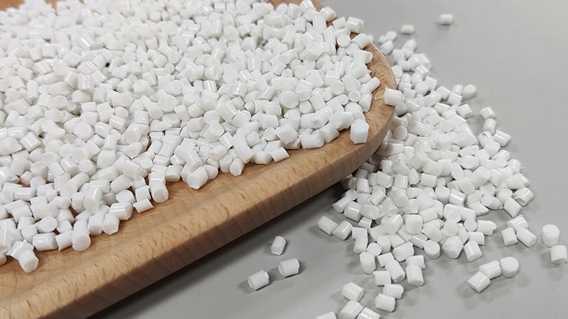 PLA+PBS biodegradable plastic pellets placed on a wooden tray with scattered granules on a clean background